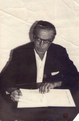 Sergio Magnani em local não identificado, sentado e lendo uma partitura. SD. Foto Petter Jacobs